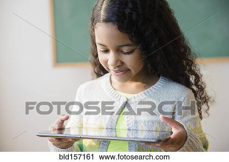 Mixed race student using digital tablet in classroom View Large Photo Image Stock Image - Mixed race student using digital tablet in classroom. Fotosearch