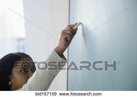Stock Photo - Mixed race student writing on chalkboard in classroom. Fotosearch