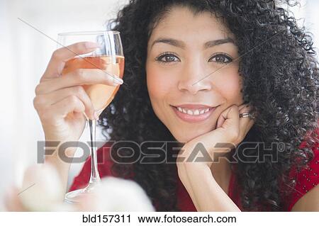 Stock Image - Mixed race woman drinking glass of wine. Fotosearch