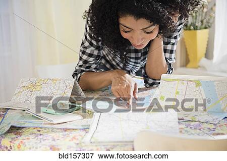 Stock Photo - Mixed race woman planning road trip with maps. Fotosearch