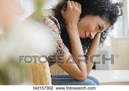 Stock Image - Mixed race woman sitting in wicker chair. Fotosearch