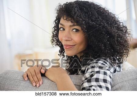 Mixed race woman sitting on sofa View Large Photo Image Stock Photo - Mixed race woman sitting on sofa. Fotosearch