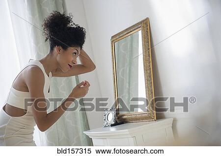 Mixed race woman styling hair in mirror View Large Photo Image Stock Photography - Mixed race woman styling hair in mirror. Fotosearch