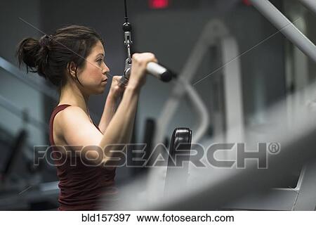 Mixed race woman using exercise machine in gym View Large Photo Image Stock Photo - Mixed race woman using exercise machine in gym. Fotosearch