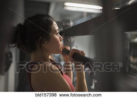 Stock Photo - Mixed race woman using exercise machine in gym. Fotosearch