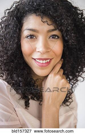 Stock Photo - Mixed race woman with curly hair smiling. Fotosearch