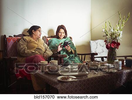 Mother and daughter using cell phone at dinner table View Large Photo Image Stock Image - Mother and daughter using cell phone at dinner table. Fotosearch