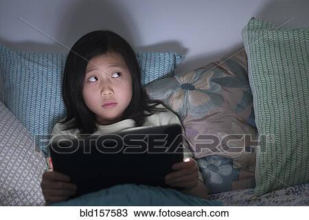Nervous Chinese girl watching digital tablet in bed View Large Photo Image Stock Image - Nervous Chinese girl watching digital tablet in bed. Fotosearch
