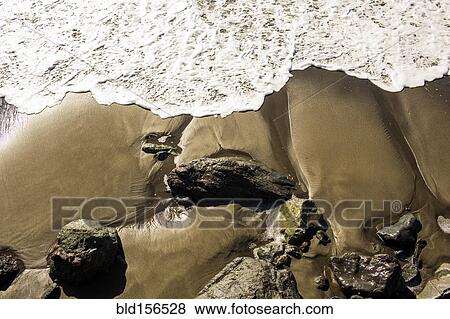 Stock Photo - Ocean waves washing up on rocky beach. Fotosearch