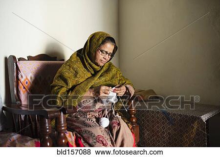 Stock Photo - Older woman knitting baby clothes. Fotosearch