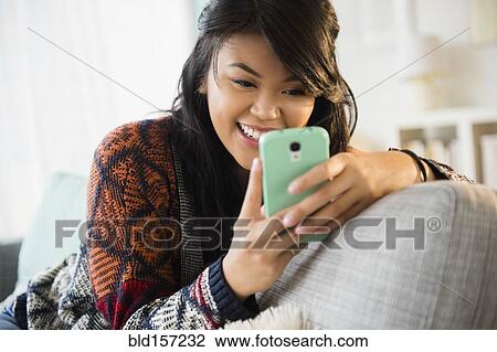 Pacific Islander texting with cell phone on sofa View Large Photo Image Stock Image - Pacific Islander texting with cell phone on sofa. Fotosearch