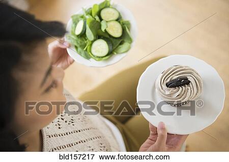 Pacific Islander woman choosing between cupcake and salad View Large Photo Image Stock Photo - Pacific Islander woman choosing between cupcake and salad. Fotosearch