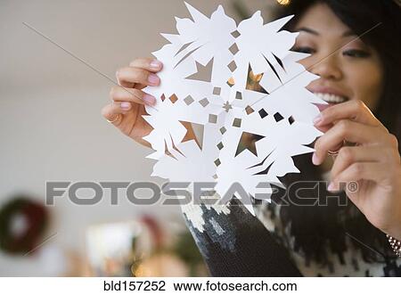 Stock Image - Pacific Islander woman holding paper snowflake. Fotosearch