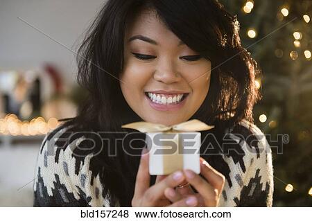 Stock Photo - Pacific Islander woman holding small wrapped gift. Fotosearch