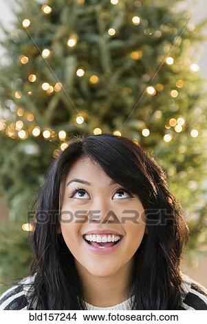 Pacific Islander woman looking up near Christmas tree View Large Photo Image Picture - Pacific Islander woman looking up near Christmas tree. Fotosearch