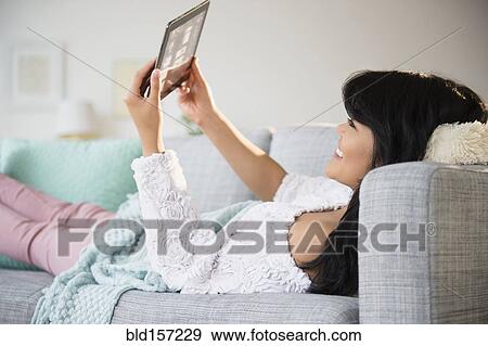 Pacific Islander woman using digital tablet on sofa View Large Photo Image Stock Photo - Pacific Islander woman using digital tablet on sofa. Fotosearch