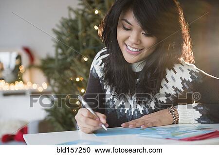 Stock Image - Pacific Islander woman writing Christmas card. Fotosearch