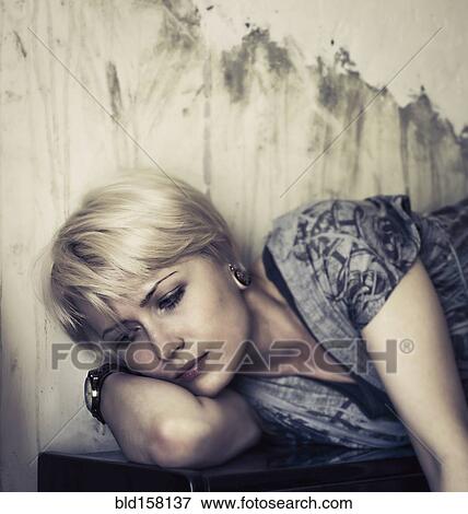 Stock Photo - Pensive Caucasian woman laying on upright piano. Fotosearch