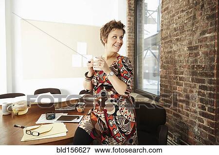 Stock Photo - Pregnant businesswoman drinking coffee in office. Fotosearch