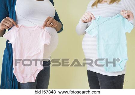 Pregnant women holding boy and girl baby clothes View Large Photo Image Stock Image - Pregnant women holding boy and girl baby clothes. Fotosearch