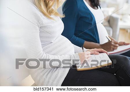 Pregnant women taking notes in class View Large Photo Image Stock Image - Pregnant women taking notes in class. Fotosearch