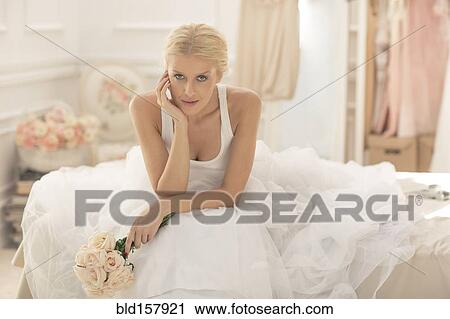 Serious bride sitting with bouquet on bed View Large Photo Image Stock Image - Serious bride sitting with bouquet on bed. Fotosearch