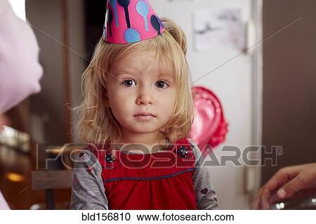 Stock Image - Serious girl wearing party hat. Fotosearch