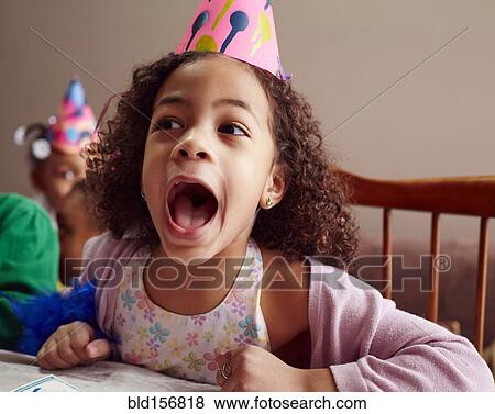 Stock Photo - Shouting girl wearing party hat with mouth open. Fotosearch