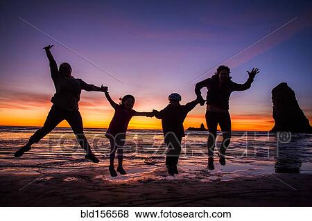 Stock Photo - Silhouette of Caucasian family jumping for joy on Cannon Beach, Oregon, United States. Fotosearch