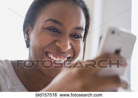 Smiling African American woman texting on cell phone View Large Photo Image Stock Photograph - Smiling African American woman texting on cell phone. Fotosearch