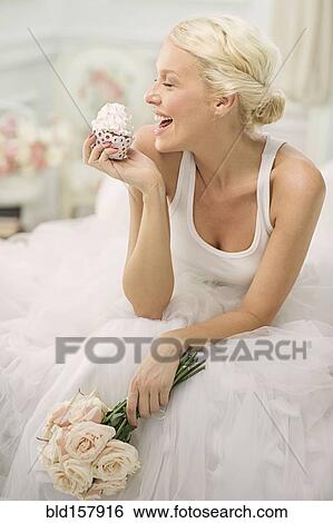 Smiling bride eating cupcake on bed View Large Photo Image Stock Photograph - Smiling bride eating cupcake on bed. Fotosearch