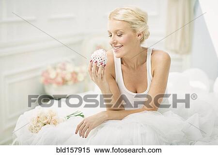Smiling bride eating cupcake on bed View Large Photo Image Stock Photography - Smiling bride eating cupcake on bed. Fotosearch