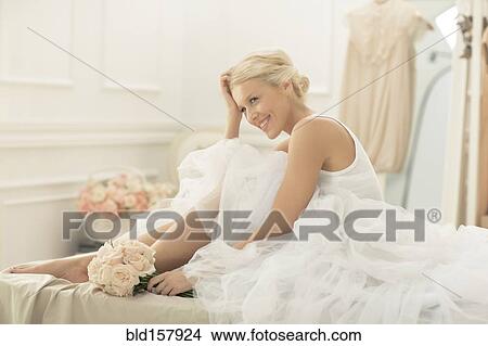 Smiling bride sitting with bouquet on bed View Large Photo Image Picture - Smiling bride sitting with bouquet on bed. Fotosearch