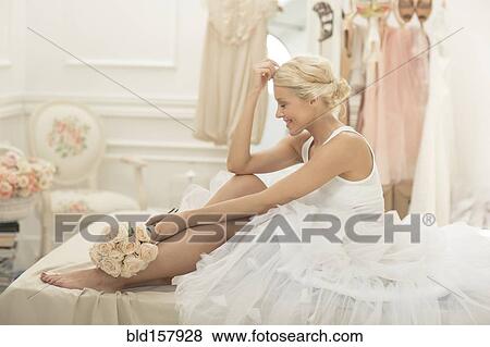 Smiling bride sitting with bouquet on bed View Large Photo Image Stock Photo - Smiling bride sitting with bouquet on bed. Fotosearch