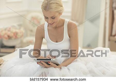 Smiling bride using digital tablet on bed View Large Photo Image Picture - Smiling bride using digital tablet on bed. Fotosearch