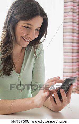 Stock Image - Smiling Caucasian woman texting on cell phone. Fotosearch