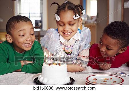 Stock Photograph - Smiling children admiring cake at party. Fotosearch