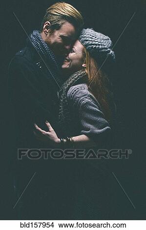 Smiling couple wearing warm clothing hugging View Large Photo Image Picture - Smiling couple wearing warm clothing hugging. Fotosearch