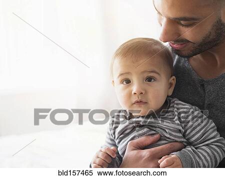 Smiling father holding baby son on bed View Large Photo Image Stock Photography - Smiling father holding baby son on bed. Fotosearch