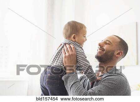 Picture - Smiling father holding baby son. Fotosearch
