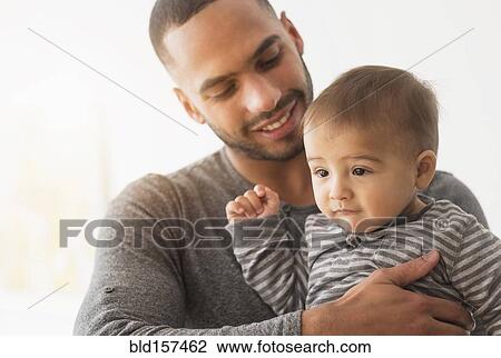 Smiling father holding baby son View Large Photo Image Stock Image - Smiling father holding baby son. Fotosearch