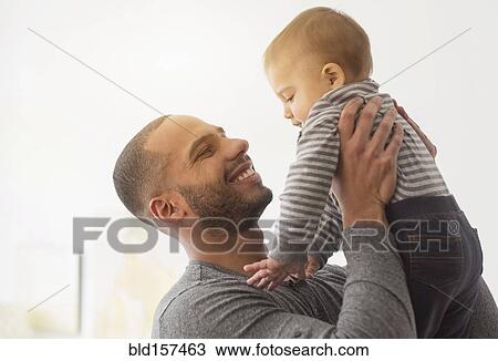 Stock Image - Smiling father playing with baby son. Fotosearch