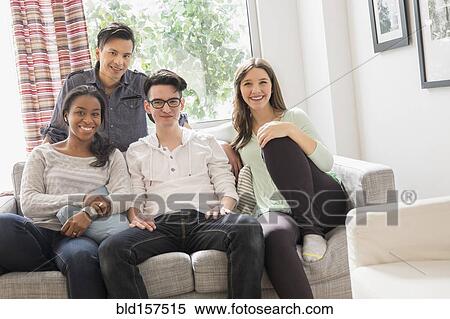 Smiling friends sitting on sofa View Large Photo Image Stock Photography - Smiling friends sitting on sofa. Fotosearch