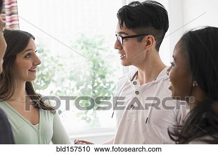 Smiling friends talking near window View Large Photo Image Stock Image - Smiling friends talking near window. Fotosearch