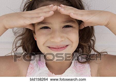 Smiling Hispanic girl shading eyes from the sun View Large Photo Image Picture - Smiling Hispanic girl shading eyes from the sun. Fotosearch