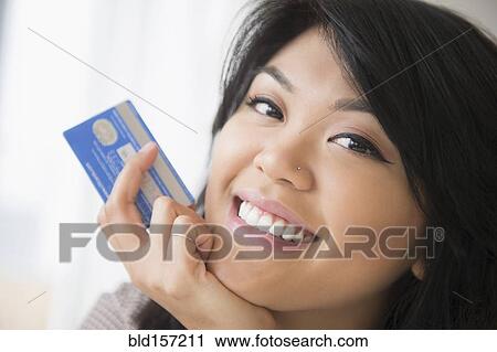 Stock Image - Smiling Pacific Islander woman holding credit card. Fotosearch
