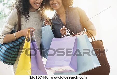 Stock Photograph - Smiling women carrying shopping bags. Fotosearch