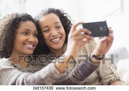 Stock Photo - Smiling women taking cell phone photograph. Fotosearch