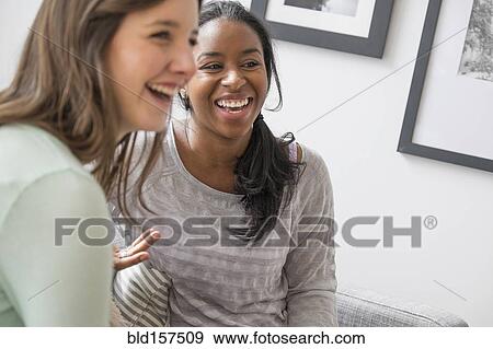 Smiling women talking on sofa View Large Photo Image Stock Photo - Smiling women talking on sofa. Fotosearch