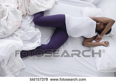 Stock Photo - Uncomfortable Black pregnant woman sleeping in bed. Fotosearch